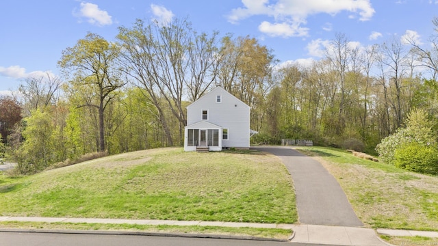 view of side of property featuring a lawn, a sunroom, and aphalt driveway