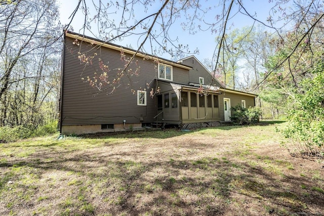 rear view of house featuring a yard and a sunroom