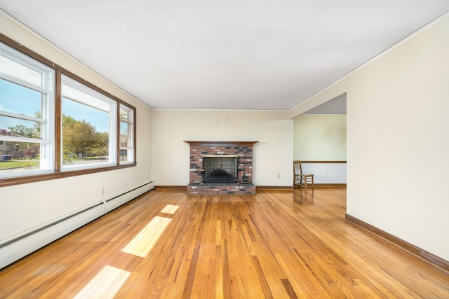 unfurnished living room with a baseboard heating unit, light wood finished floors, a fireplace, baseboards, and crown molding