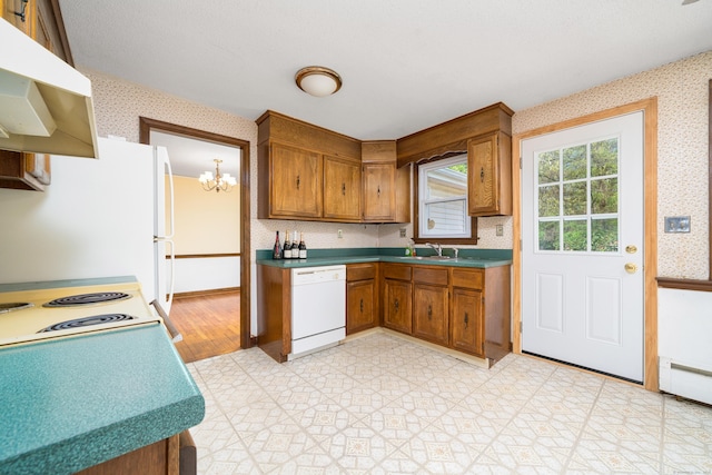 kitchen with white appliances, wallpapered walls, brown cabinetry, under cabinet range hood, and a chandelier