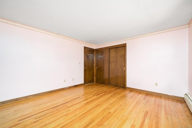 unfurnished bedroom featuring light wood-type flooring, baseboards, a closet, and a baseboard heating unit
