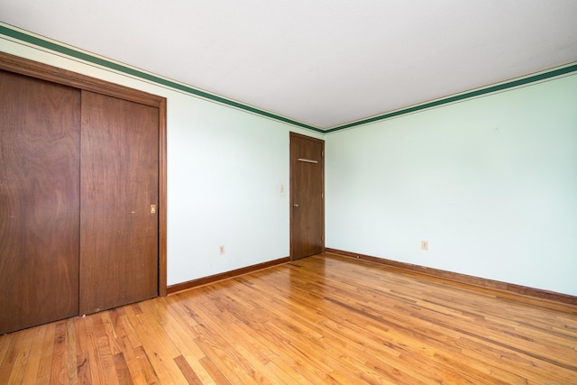 unfurnished bedroom with baseboards, light wood finished floors, and a closet