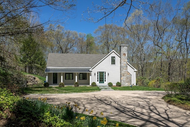 view of front of property featuring a shingled roof, a front yard, and a chimney