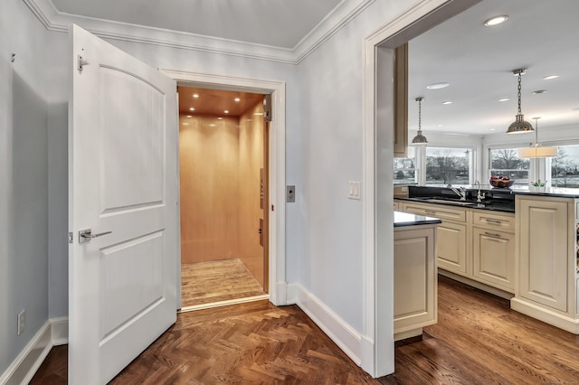 hallway featuring crown molding, baseboards, recessed lighting, and a sink