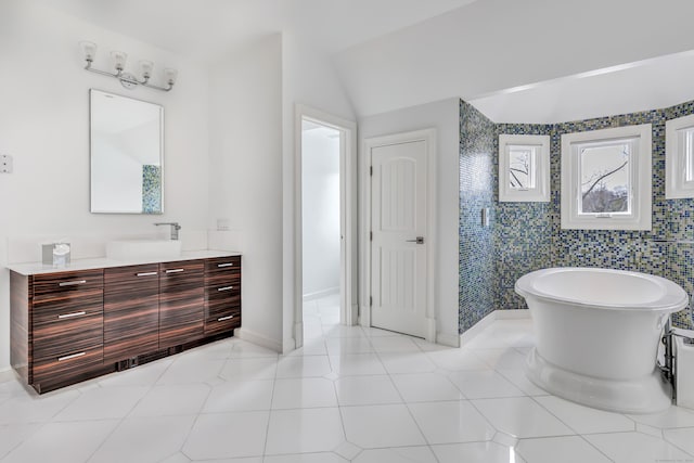 full bath with a freestanding tub, baseboards, vaulted ceiling, and vanity