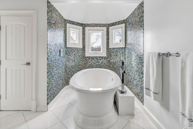 bathroom with a freestanding bath, tile walls, baseboards, and tile patterned floors