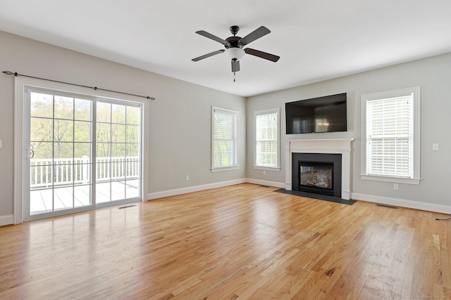 unfurnished living room with ceiling fan, visible vents, a fireplace with flush hearth, baseboards, and light wood-style floors
