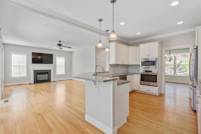 kitchen with a sink, stainless steel appliances, a peninsula, a wealth of natural light, and visible vents