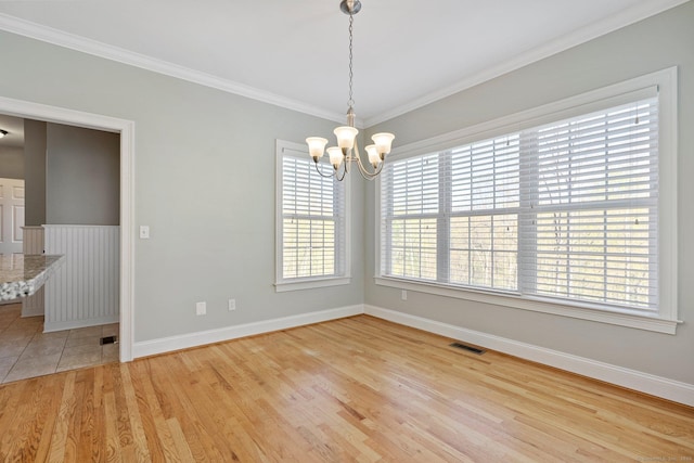 unfurnished dining area featuring visible vents, crown molding, baseboards, light wood-style flooring, and a notable chandelier