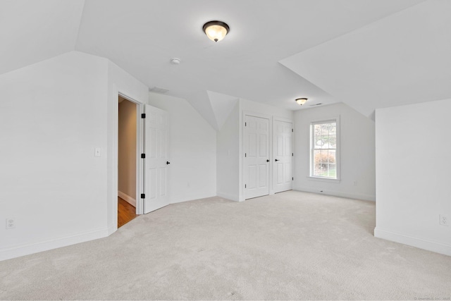 additional living space with baseboards, vaulted ceiling, and light carpet