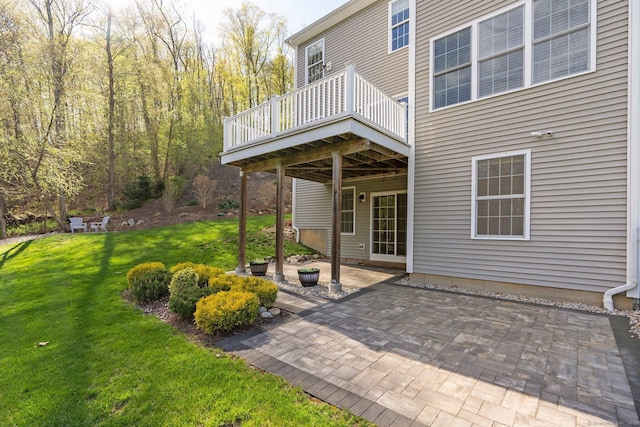 rear view of property featuring a yard, a deck, and a patio