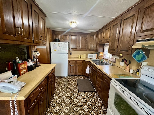 kitchen featuring white appliances, under cabinet range hood, a sink, and light countertops
