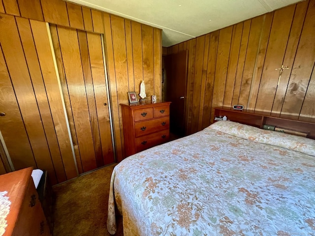 bedroom with wooden walls and dark colored carpet