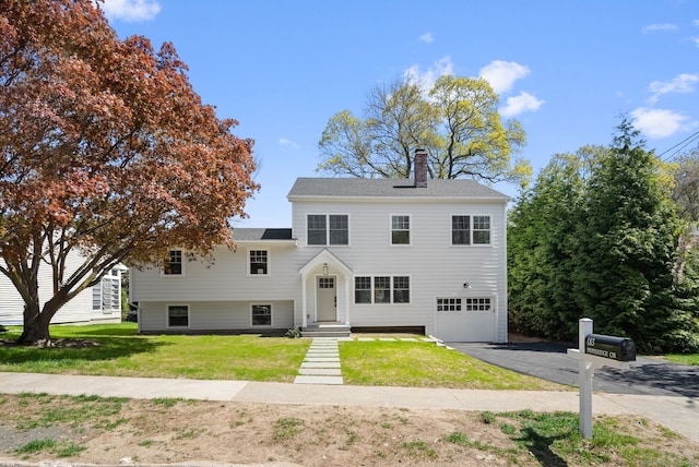183 Pepperidge Cir, Fairfield, CT 06824 - view of front facade with asphalt driveway, a garage, a chimney, and a front lawn