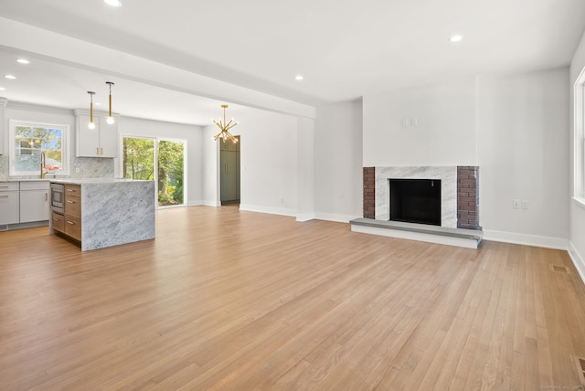 183 Pepperidge Cir, Fairfield, CT 06824 - unfurnished living room with light wood-type flooring, a chandelier, recessed lighting, baseboards, and a fireplace