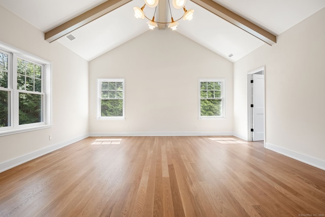 spare room featuring plenty of natural light, light wood-style floors, and an inviting chandelier