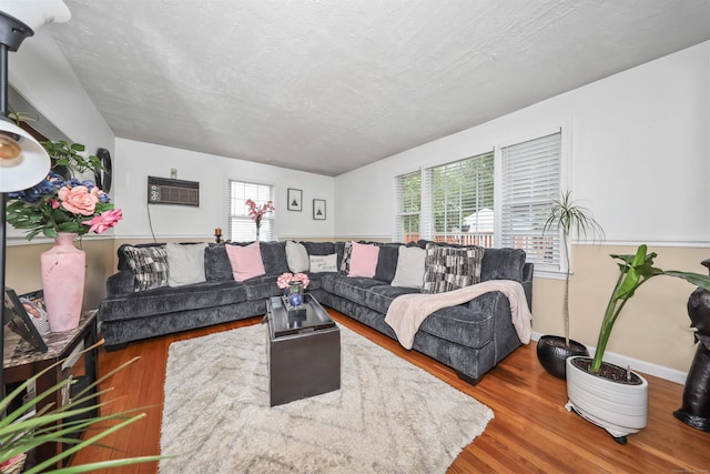 839 Washington Avenue Extension, Waterbury, CT 06708 - living room featuring wood finished floors, a wall unit AC, a textured ceiling, and baseboards