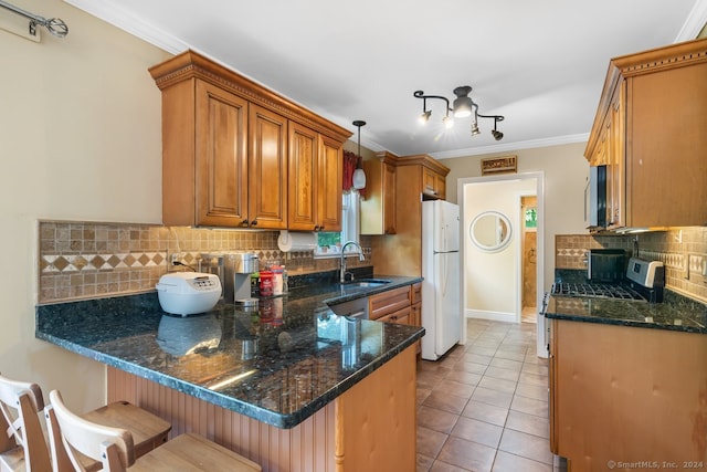 kitchen featuring a sink, brown cabinetry, freestanding refrigerator, a peninsula, and tasteful backsplash