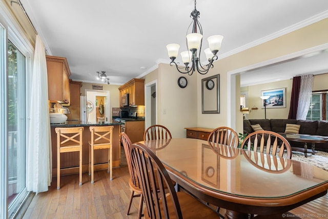 dining room featuring crown molding, light wood finished floors, and a chandelier