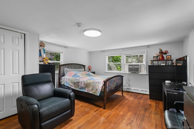 bedroom featuring wood finished floors, a baseboard heating unit, multiple windows, and cooling unit