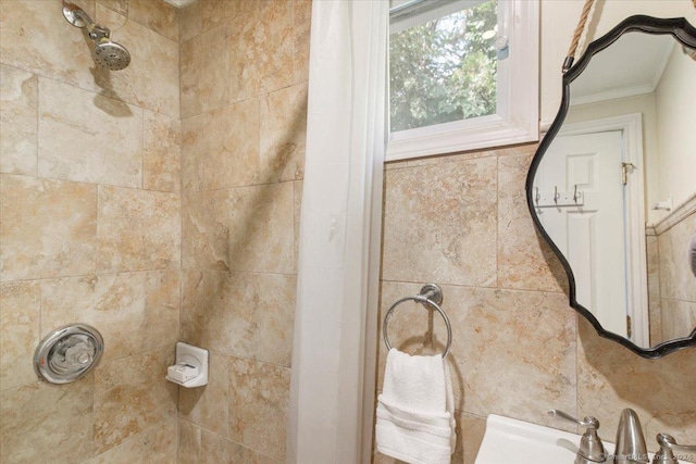 full bathroom featuring a sink, ornamental molding, and tiled shower