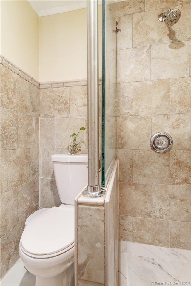 bathroom with tile walls, toilet, and tiled shower