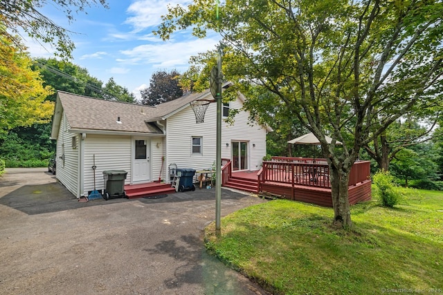 back of property featuring a lawn, a shingled roof, and a wooden deck