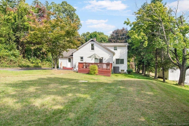 rear view of house with a yard, a deck, and a chimney