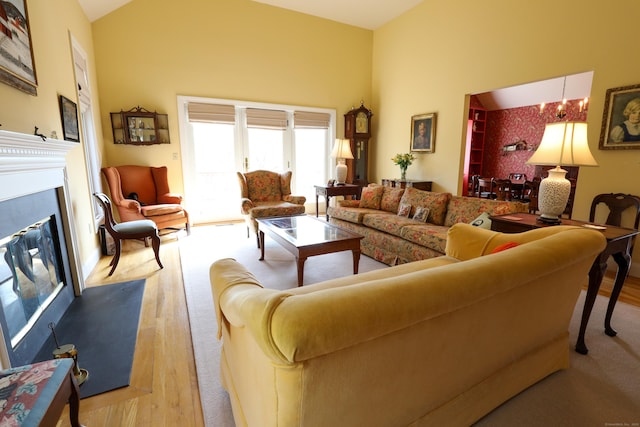 living area with wood finished floors, a glass covered fireplace, and high vaulted ceiling