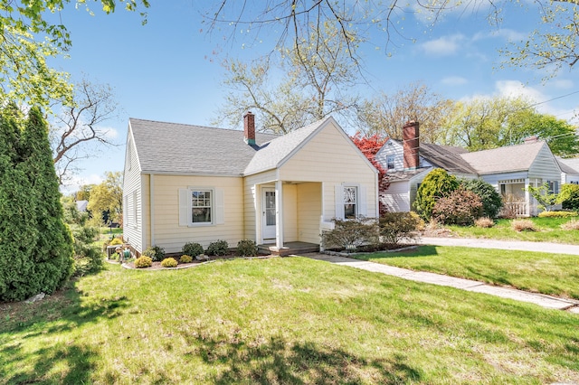view of front of home with roof with shingles and a front yard