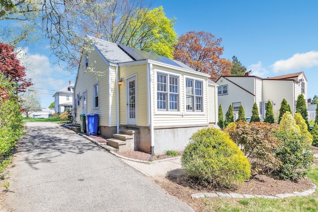 view of side of home with entry steps and aphalt driveway
