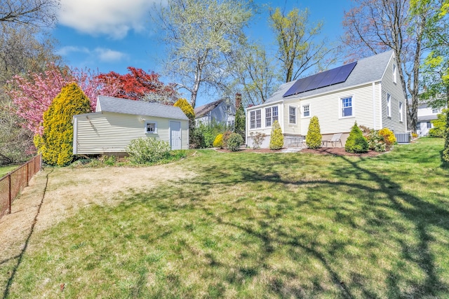 view of yard featuring fence, central AC unit, and an outdoor structure