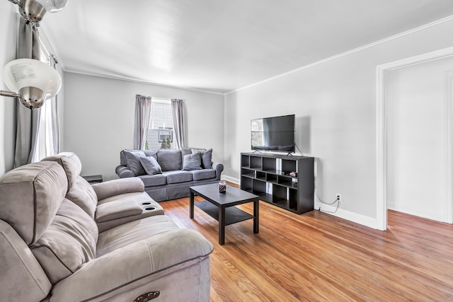 living area with crown molding, baseboards, and light wood-style flooring
