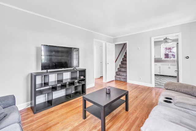 living room with crown molding, baseboards, stairs, and wood finished floors