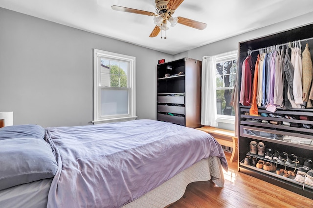 bedroom with a ceiling fan, multiple windows, and wood finished floors