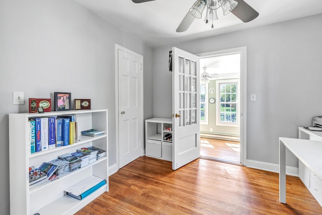 interior space featuring a ceiling fan, baseboards, and wood finished floors