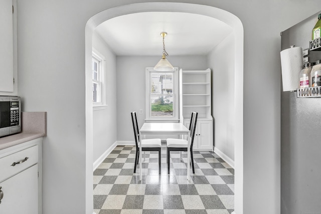 dining space with baseboards, arched walkways, and dark floors