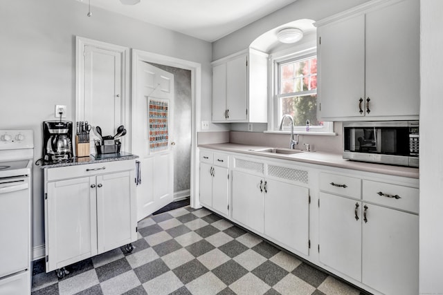 kitchen featuring white range with electric cooktop, stainless steel microwave, white cabinets, dark floors, and a sink