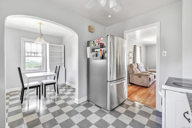 kitchen with dark floors, arched walkways, freestanding refrigerator, and electric range