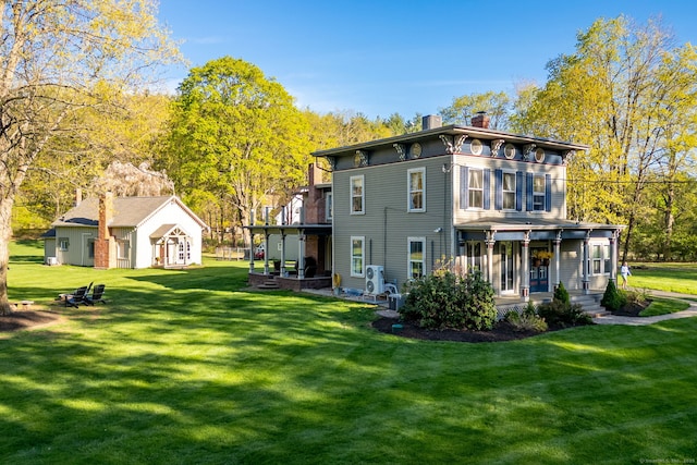 back of house featuring a lawn, covered porch, and a chimney
