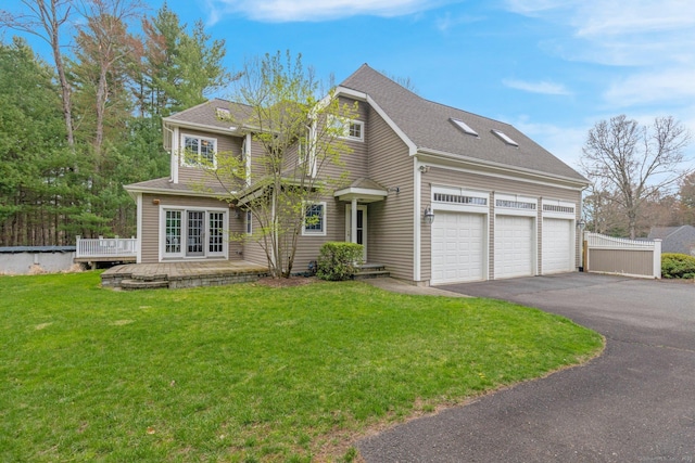 view of front of home with an attached garage, a wooden deck, driveway, and a front yard