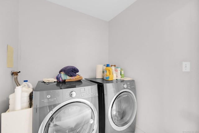 washroom featuring independent washer and dryer, laundry area, and baseboards