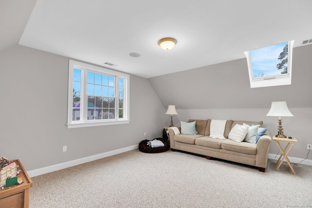 living area featuring visible vents, carpet flooring, baseboards, and vaulted ceiling with skylight