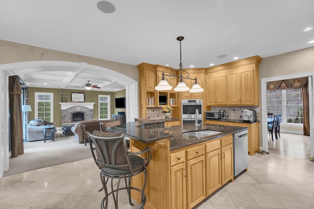 kitchen featuring ceiling fan, appliances with stainless steel finishes, a sink, arched walkways, and open floor plan