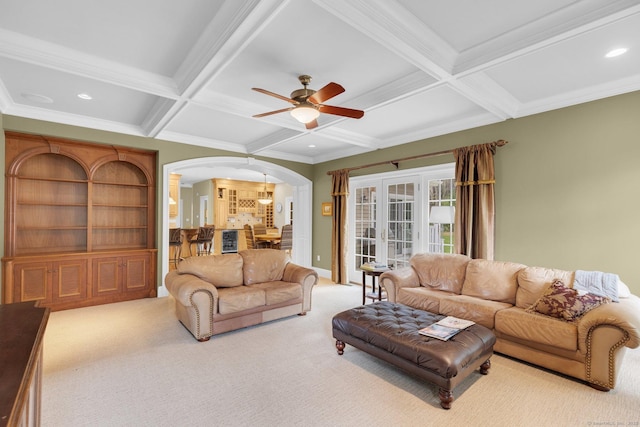 carpeted living area featuring arched walkways, a ceiling fan, beamed ceiling, ornamental molding, and coffered ceiling