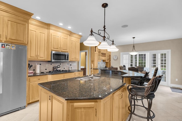 kitchen featuring stainless steel appliances, tasteful backsplash, a sink, and light brown cabinets
