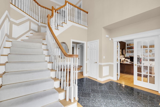 staircase featuring baseboards, granite finish floor, and a towering ceiling
