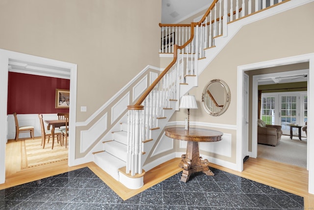 stairway with baseboards, a high ceiling, and french doors