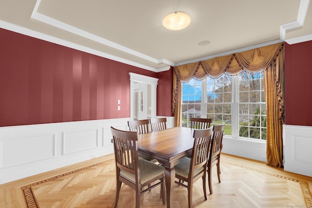 dining space with ornamental molding, a wainscoted wall, and wallpapered walls