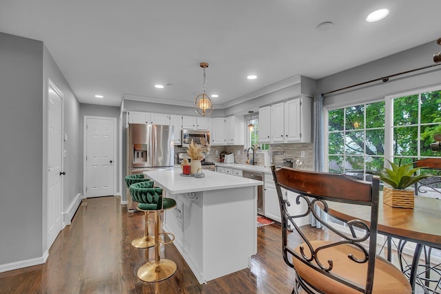 kitchen featuring stainless steel appliances, light countertops, a center island, white cabinets, and dark wood finished floors